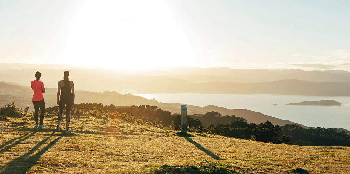 Two people silhouetted against the sunrise at the top of Mt Kaukau